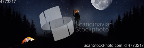 Image of Halloween theme: scary maniac with pumpkin head in dark forest
