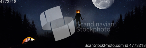 Image of Halloween theme: scary maniac with pumpkin head in dark forest