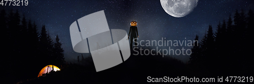 Image of Halloween theme: scary maniac with pumpkin head in dark forest