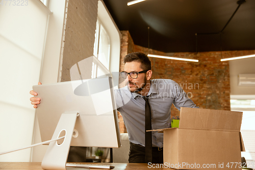 Image of A young businessman moving in office, getting new work place