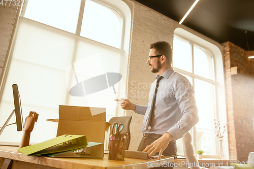 Image of A young businessman moving in office, getting new work place