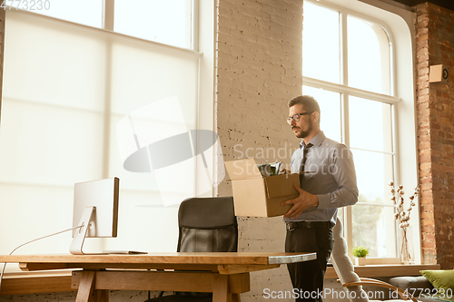 Image of A young businessman moving in office, getting new work place