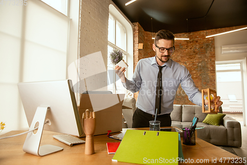 Image of A young businessman moving in office, getting new work place