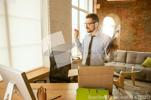 Image of A young businessman moving in office, getting new work place