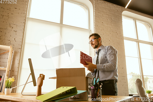 Image of A young businessman moving in office, getting new work place