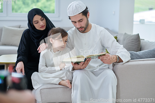 Image of Young muslim family reading Quran during Ramadan