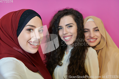 Image of Muslim women taking selfie by mobile phone isolated on pink background