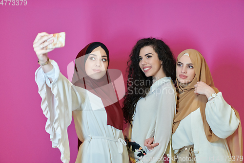 Image of Muslim women taking selfie by mobile phone isolated on pink background