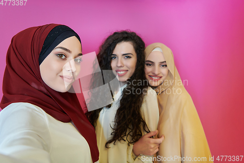 Image of Muslim women taking selfie by mobile phone isolated on pink background