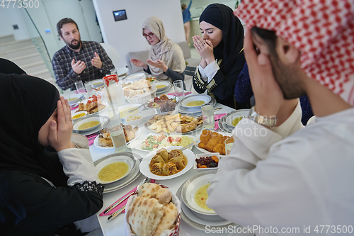 Image of Muslim family making iftar dua to break fasting during Ramadan.