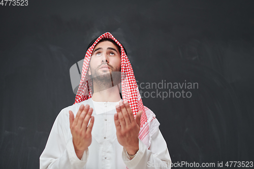 Image of Arab man in traditional clothes praying to God or making dua