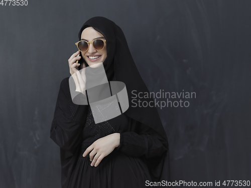 Image of Young muslim businesswoman in traditional clothes or abaya using smartphone