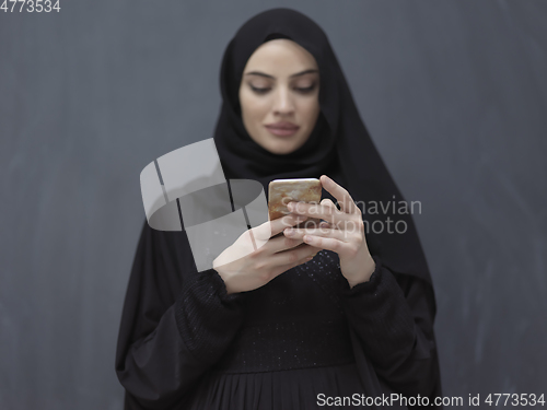 Image of Young muslim businesswoman in traditional clothes or abaya using smartphone