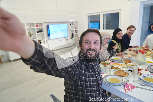 Image of Muslim family taking selfie while having iftar together during Ramadan