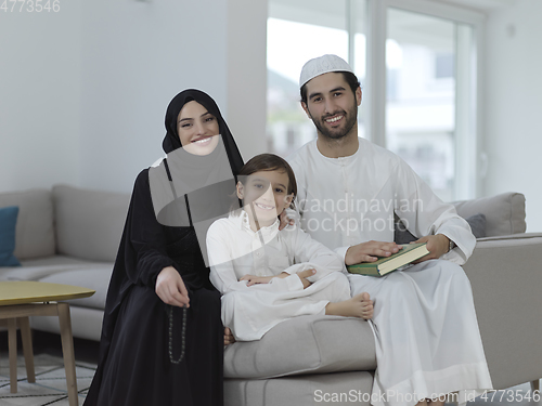 Image of Young muslim family reading Quran during Ramadan