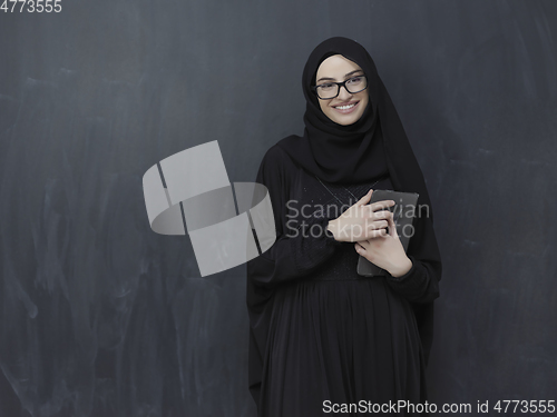 Image of Young Arab businesswoman in traditional clothes or abaya with tablet computer