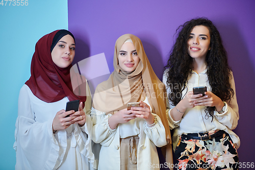 Image of Muslim women using mobile phones isolated on blue and purple background