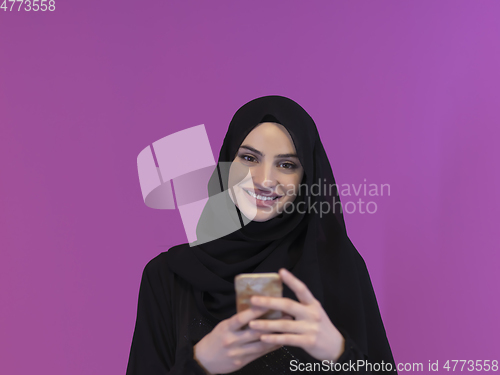 Image of Young muslim businesswoman in traditional clothes or abaya using smartphone