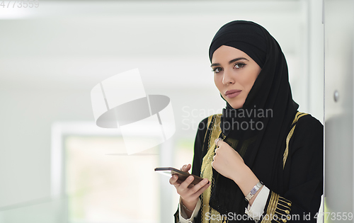Image of Portrait of Arab woman in traditional clothes using mobile phone