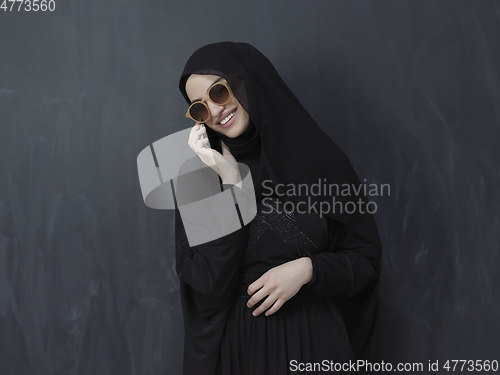 Image of Young muslim businesswoman in traditional clothes or abaya using smartphone