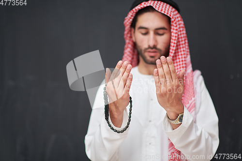 Image of Arab man in traditional clothes praying to God or making dua