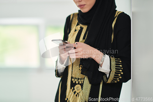 Image of Portrait of Arab woman in traditional clothes using mobile phone