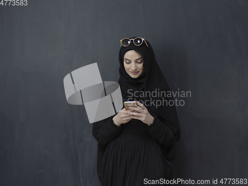 Image of Young muslim businesswoman in traditional clothes or abaya using smartphone