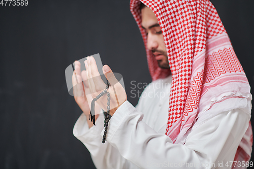 Image of Arab man in traditional clothes praying to God or making dua