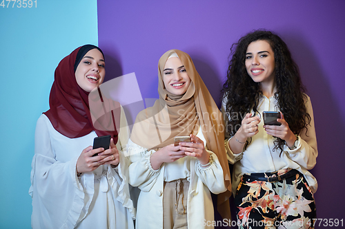 Image of Muslim women using mobile phones isolated on blue and purple background