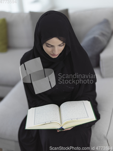 Image of Portrait of young muslim woman reading Quran in modern home