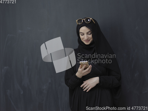 Image of Young muslim businesswoman in traditional clothes or abaya using smartphone