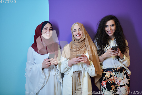 Image of Muslim women using mobile phones isolated on blue and purple background
