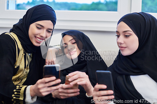 Image of Portrait of Arabian girls wearing modern abaya using mobile phone