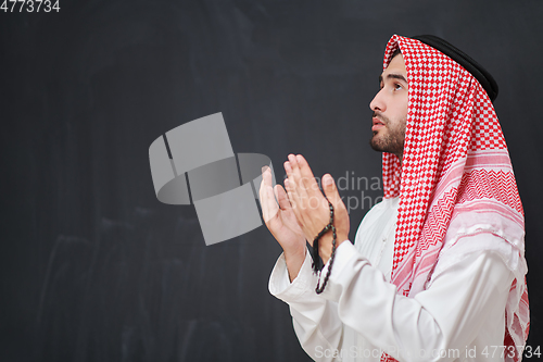 Image of Arab man in traditional clothes praying to God or making dua