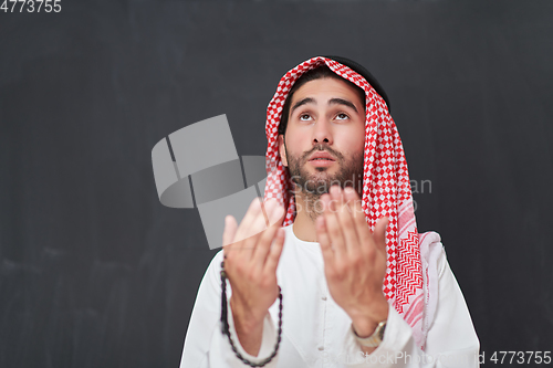 Image of Arab man in traditional clothes praying to God or making dua