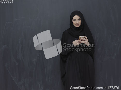 Image of Young muslim businesswoman in traditional clothes or abaya using smartphone