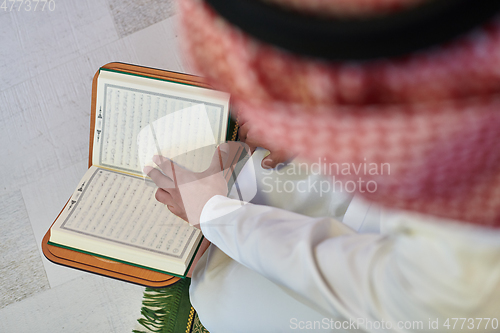Image of Young muslim man reading Quran during Ramadan