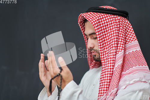 Image of Arab man in traditional clothes praying to God or making dua