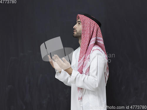 Image of Arab man in traditional clothes praying to God or making dua