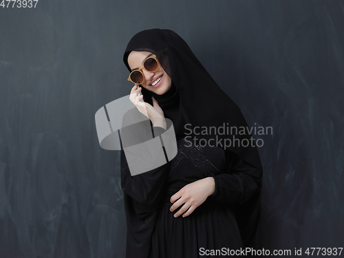 Image of Young muslim businesswoman in traditional clothes or abaya using smartphone