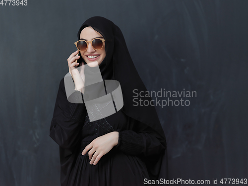 Image of Young muslim businesswoman in traditional clothes or abaya using smartphone