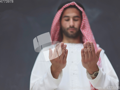 Image of Arab man in traditional clothes praying to God or making dua