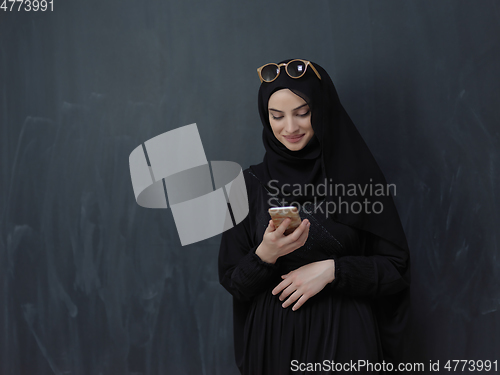 Image of Young muslim businesswoman in traditional clothes or abaya using smartphone