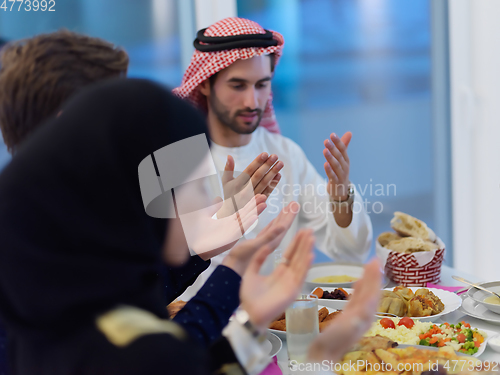 Image of Muslim family making iftar dua to break fasting during Ramadan
