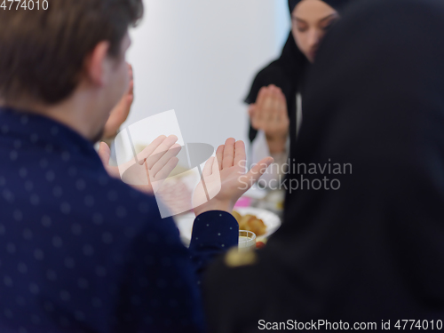 Image of Muslim family making iftar dua to break fasting during Ramadan