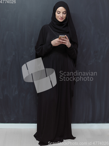 Image of Young muslim businesswoman in traditional clothes or abaya using smartphone