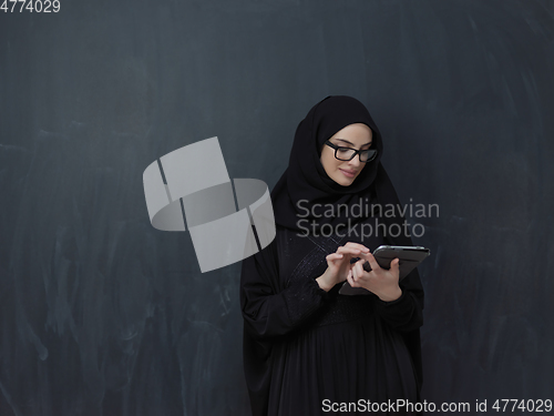 Image of Young Arab businesswoman in traditional clothes or abaya with tablet computer