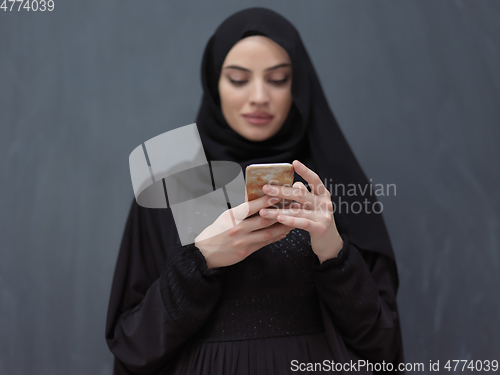 Image of Young muslim businesswoman in traditional clothes or abaya using smartphone