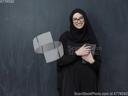 Image of Young Arab businesswoman in traditional clothes or abaya with tablet computer