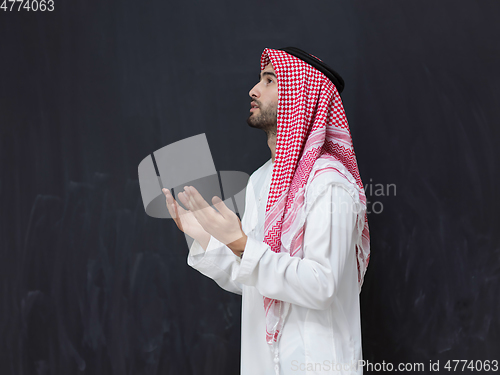 Image of Arab man in traditional clothes praying to God or making dua